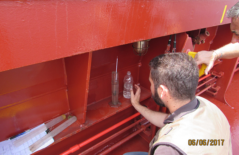 Marine surveyor conducting draft survey inspection inside cargo hold during loading operations.