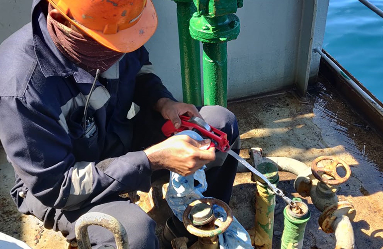 Surveyor performing draft survey measurements and recording vessel data for cargo calculation.