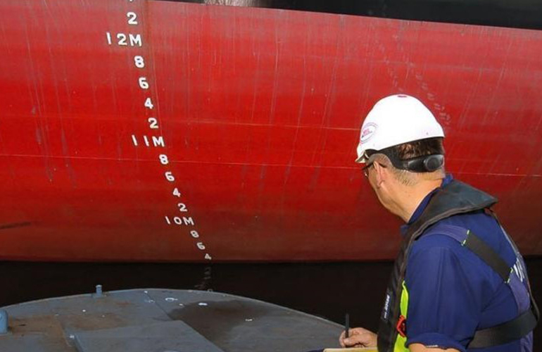 Draft surveyor checking vessel draft marks at hull to verify cargo loading quantity.