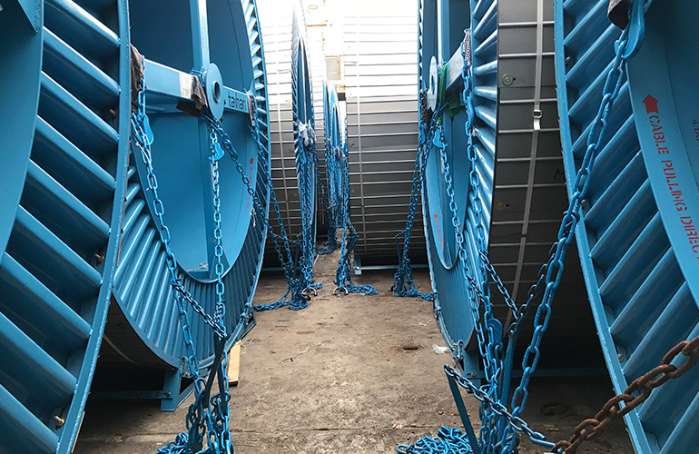 Surveying large blue lattice structures prepared for shipping as breakbulk cargo.